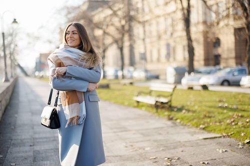 Una mujer con abrigo y bufanda pasea por la ciudad
